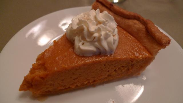 Slice of pumpkin pie with cream on top