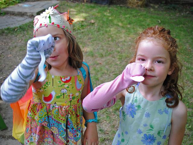 Girls dressed up in a garden holding sock puppets