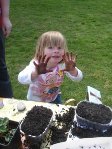 Child with muddy hands planting
